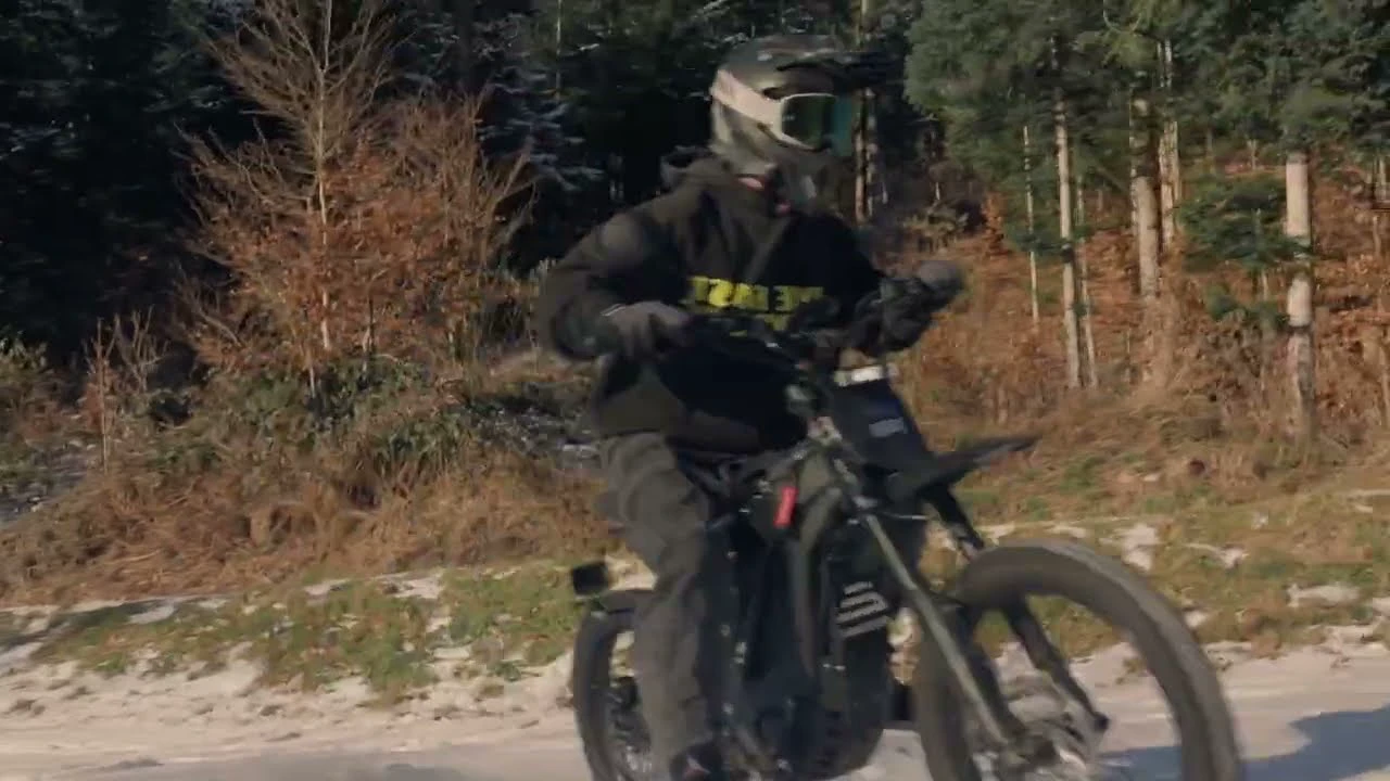 A helmeted rider on an E Ride Pro electric bike beside a forest.